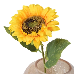 Realistic artificial sunflower with yellow petals and green leaves in a glass vase