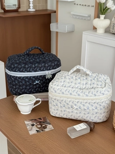Detailed close-up of quilted floral makeup bags with bow accents and flower zipper pulls