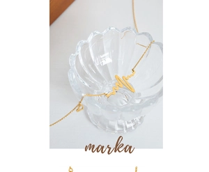 Close-up of golden heartbeat pendant on fine chain in decorative shell glass dish