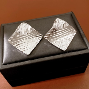 Macro view of geometric rhombic earrings with water ripple texture in silver finish