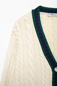 Close-up of cable knit texture on ivory V-neck cardigan with striped ribbed trim