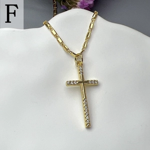 Close-up of golden cross pendant with micro-inlaid zircons on white ceramic stand