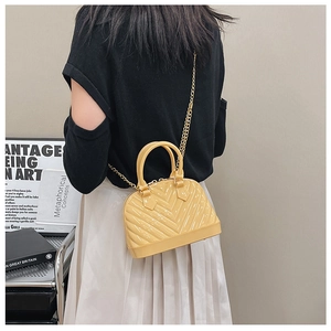 Detail of a mini yellow shell bag with glossy finish and gold chain strap on shoulder