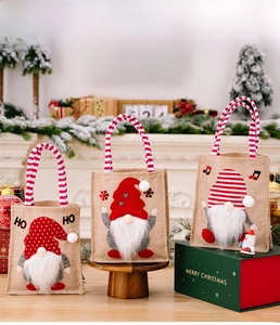 Three burlap Christmas gift bags with gnome dolls on a cozy wooden holiday background