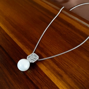 Vue détaillée du pendentif en zircone carrée et perle sur un collier en argent élégant