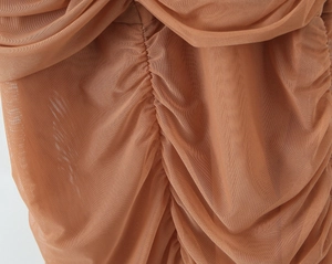 Détail du tissu en maille caramel avec fronces délicates et texture ondulée sur la robe