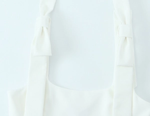 Detailed view of elegant white bow shoulder strap made of soft woven textured fabric