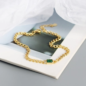 Detail of s925 silver gold-plated tank chain bracelet with emerald green gemstone