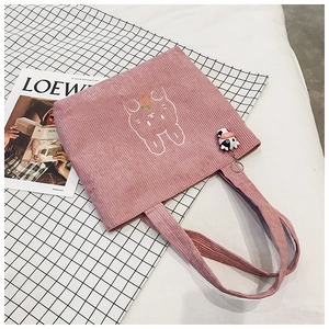 Detail of pink corduroy tote bag with rabbit embroidery and a small cow plush keychain