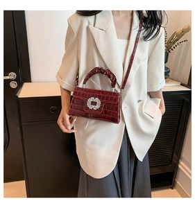 Détail du sac en cuir croco rouge foncé avec une boucle carrée ornée de strass brillants