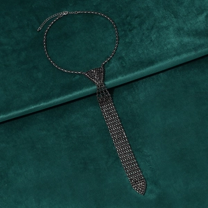 Detailed view of tie-shaped necklace featuring black rhinestones on green velvet
