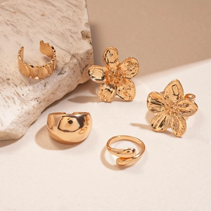 Detailed view of five-piece gold flower rings displayed on a natural stone base