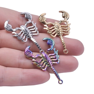 Detailed macro view of gold, silver, and rainbow scorpion pendants on fingertips