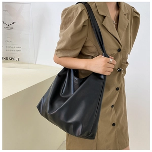 Detail view of large black matte PU leather tote bag worn as a shoulder hobo bag