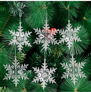 Detailed close-up of six transparent snowflake ornaments hanging on a green Christmas tree