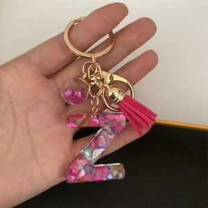 Detail of resin letter Z keychain with pink sequins, shell flakes and pompom ball