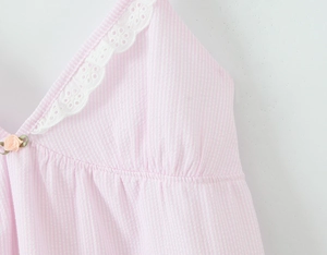 Detail of pink striped dress featuring white floral lace trim and delicate fabric flowers