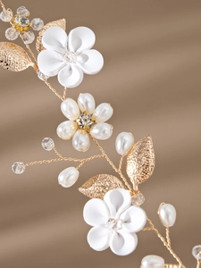 Detailed close-up of golden bridal headband with white ceramic flowers and pearls