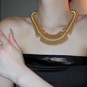 Detail of layered gold metal spring coil necklace with high-gloss finish on neck