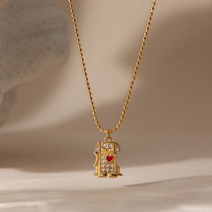 Macro shot of gold robot dog pendant with red heart and crystals on beaded chain