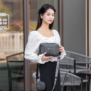 Detail of black V-quilted crossbody bag set featuring a round coin purse on fabric strap
