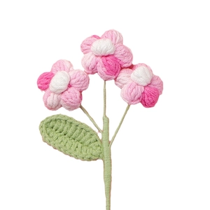 Handmade crochet puff flowers with pink petals and green leaves on white background