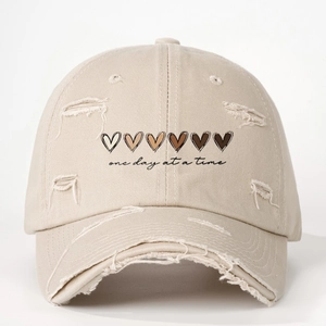 Vintage khaki washed baseball cap with hearts and 'one day at a time' slogan and distressed holes