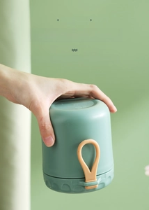 Leakproof stainless steel breakfast cup being held upside down by a portable strap