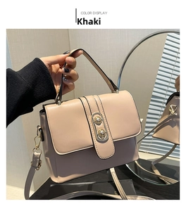 Detail of khaki leather handbag with gold oval metal buckle and detachable strap