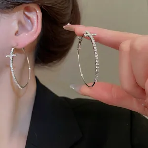 Boucles d'oreilles créoles argentées avec motif croix et cristaux brillants sertis