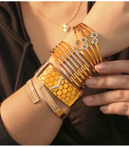 Detail of gold stacked bangle set featuring cutout tree of life and pavé crystal designs