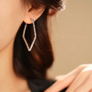 Silver geometric rhombus hoop earrings with textured finish worn by model in a side view