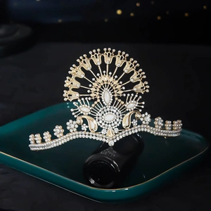Close-up of golden bridal crown with pearls and rhinestones on a dark ceramic plate
