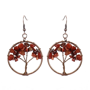 Detail showing the wire-wrapped tree of life design on handmade bronze earrings with red stones