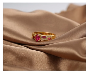 Close-up of gold-plated ring with red oval center stone and white zircon accents