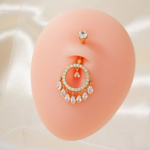 Detailansicht eines goldenen Bauchnabelpiercings mit funkelnden Zirkon-Tropfenanhängern