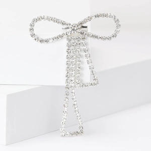 Detail of silver rhinestone bow brooch with elegant hanging chains on white cubes