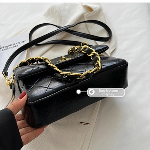 Detail of the diamond quilted bag bottom with gold chain handle and shiny black finish