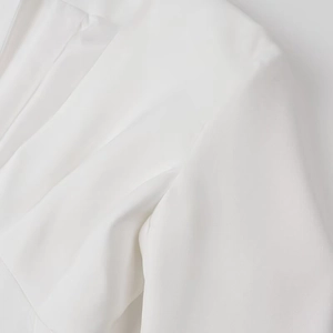 Close-up of white woven fabric detail showing structured shoulder and sharp stitching