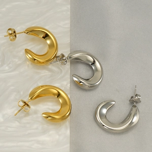 Fashionable gold and silver C-shaped titanium steel hoop earrings on a textured background