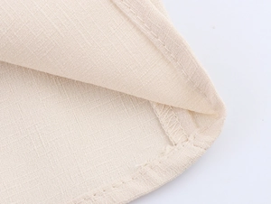 Detail view of beige linen blouse hem featuring high-quality double stitching and texture