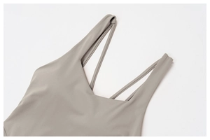 Detail of square neckline and thin criss-cross shoulder straps on a grey yoga bodysuit