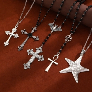 Flat lay of diverse Gothic necklaces featuring silver cross, bat, and star pendants on leather