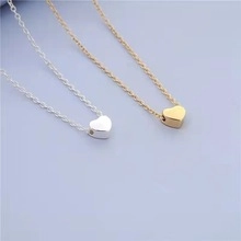 Detail of elegant gold heart pendant on a layered double snake chain necklace