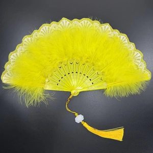 Close-up of yellow feather folding fan with intricate hollow patterns and silk tassel
