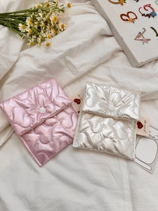 Detail of pink and white heart-quilted satin pouches with button closure on soft fabric