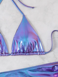 Detail shot of holographic purple blue bikini set with metallic finish on marble background