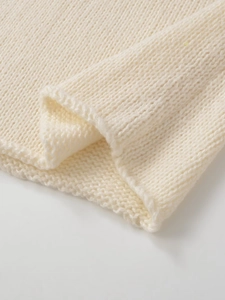 Detailansicht der feinen weißen Stricktextur und des weichen Stoffes des Damenpullovers