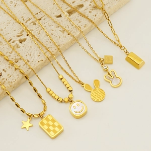 Detail of assorted 18K gold plated necklaces featuring smile, rabbit, and gold bar charms