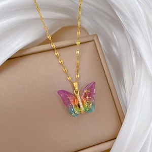 Close-up of golden butterfly pendant with purple gradient glitter and tiny diamonds